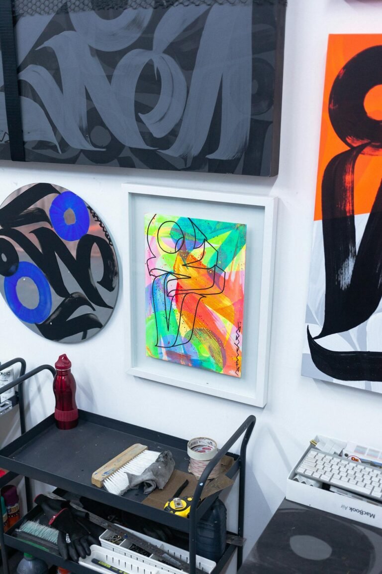 A colorful display of abstract paintings on a white wall in an indoor art gallery.