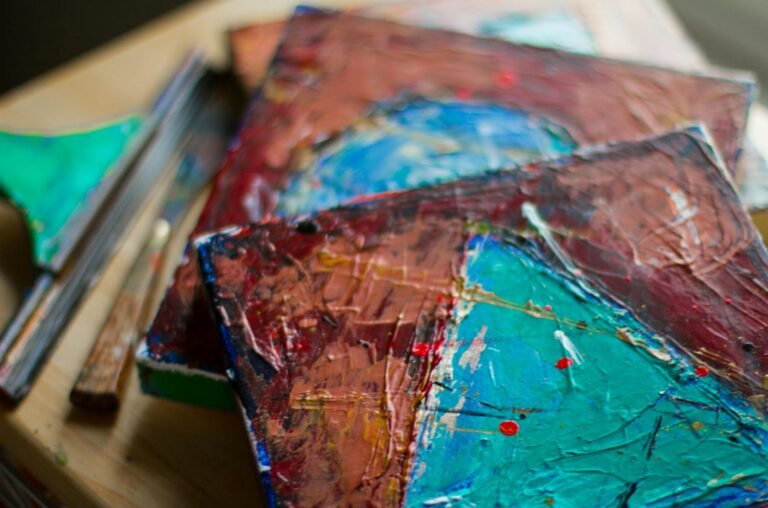 Close-up of vibrant abstract acrylic paintings showcasing rich textures on canvas.
